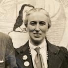 Cropped newspaper photo of Clemence Housman wearing suffrage buttons and standing in front of a suffrage banner