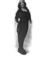 a full-body portrait of Lydia Taylor wearing a long dress and hat