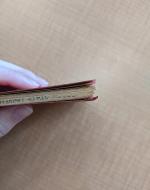 A hand holds the book with the signatures pointed away from the palm, demonstrating the way the signatures are no longer even.