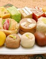 A variety of colorful Bengali sweets arranged on a plate.