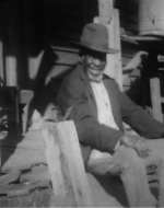 a still shot from documentary footage showing a man sitting on a porch
