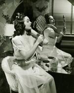 A woman examining herself with a mirror.