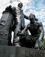 A male figure representing Abraham Lincoln stands with his arm reached out over another male figure