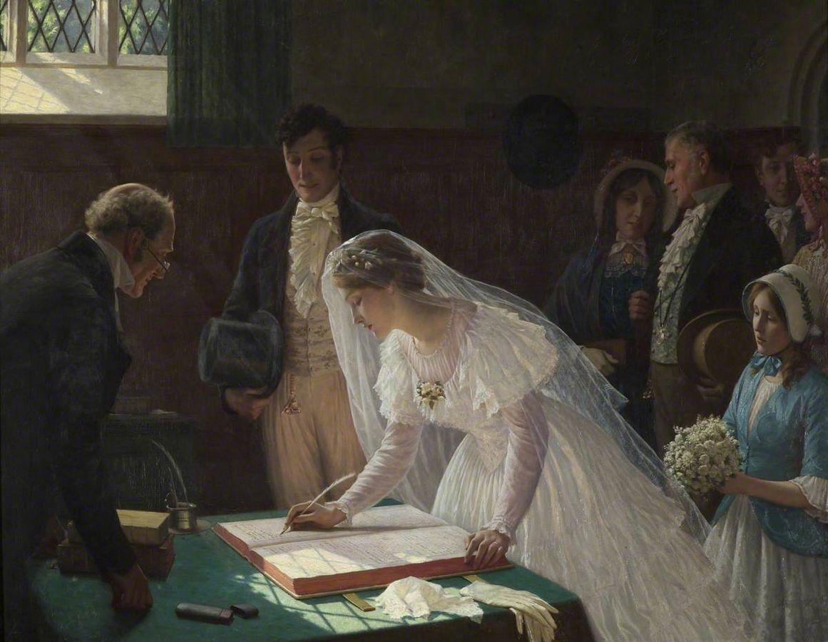 A bride signs the wedding register in front of her husband and the officiant; friends and family in the background.