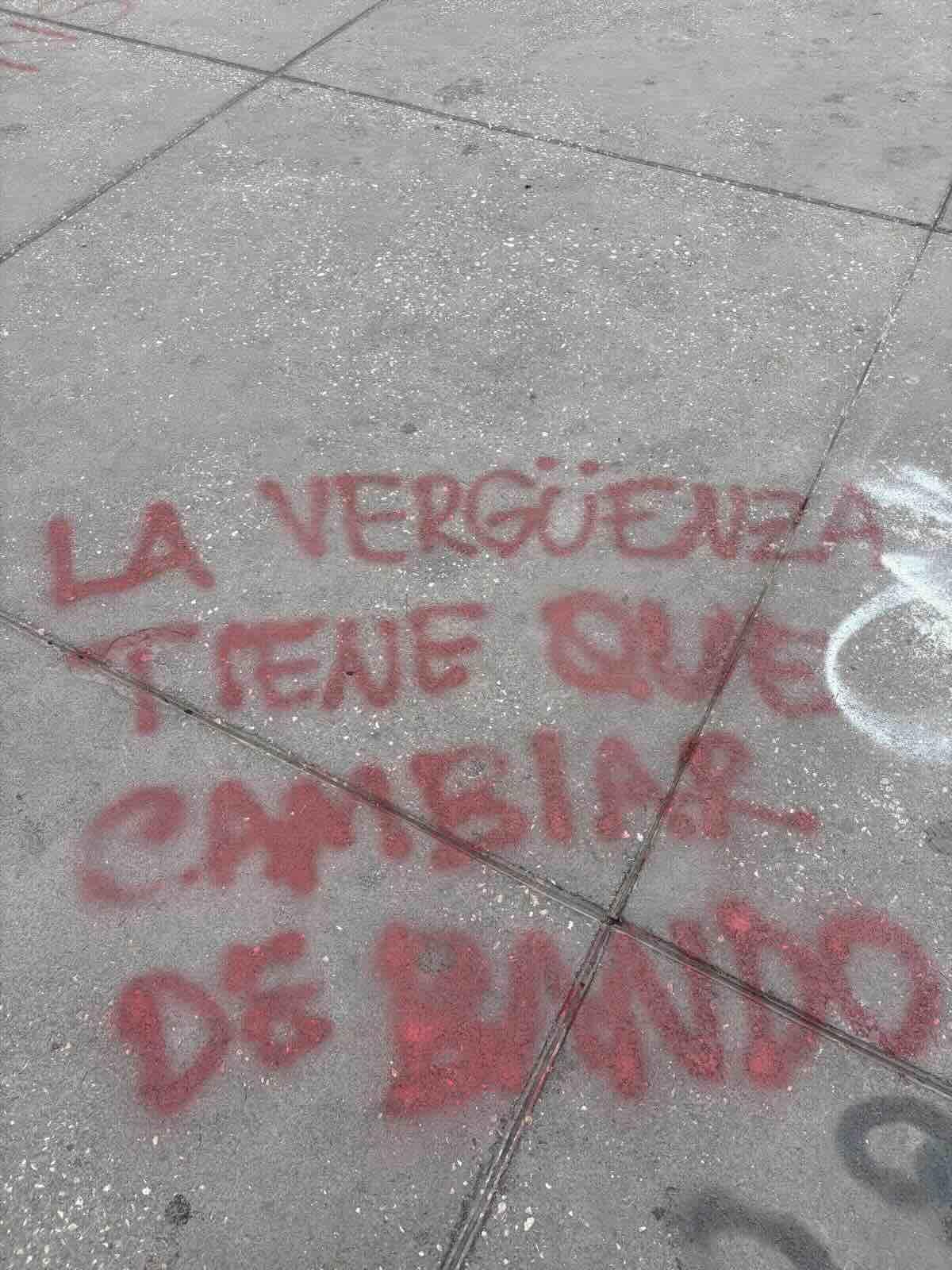 graffiti on ground: La vergüenza tiene que cambiar de bando (shame has to change side)
