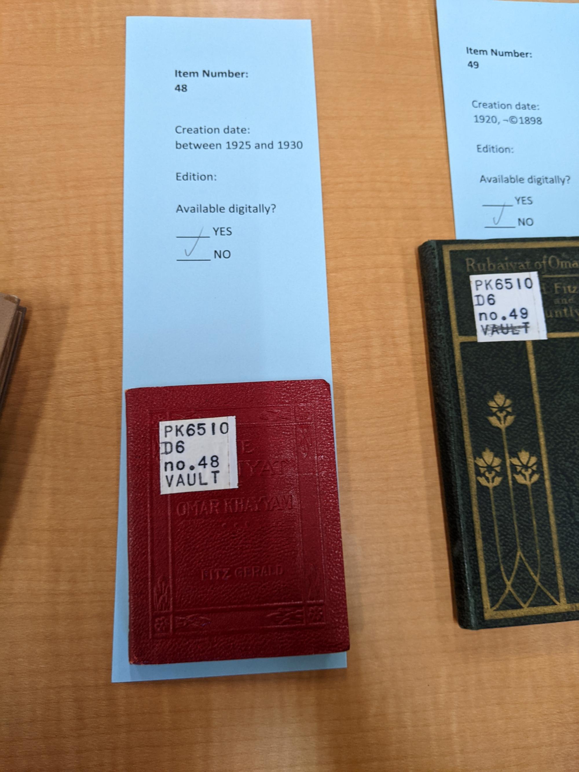 A small red book sitting on a blue slip of paper labeled: "Item Number 48, Creation date 1925-1930, Edition available digitally? NO"