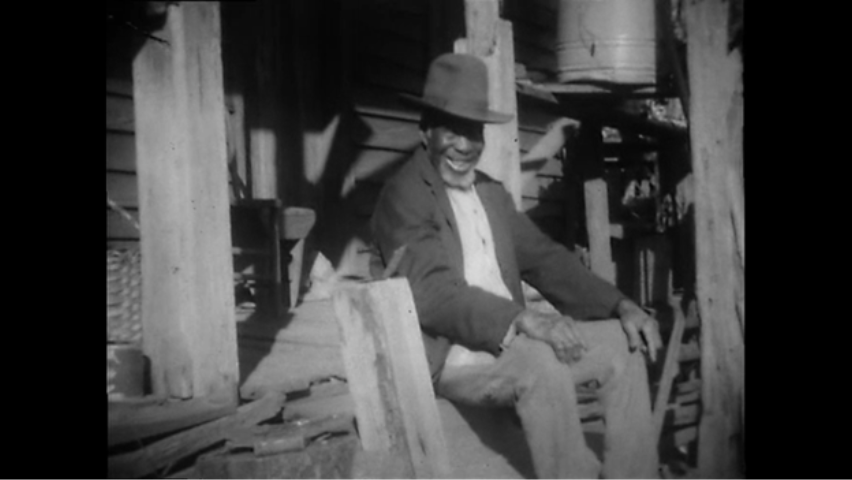 a still shot from documentary footage showing a man sitting on a porch